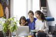 © Cavan Images - Cheerful mother and daughters doing video call with laptop at home
