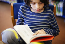 Boy Reading Book In Library