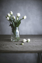 White Roses In Jar On Wooden Table