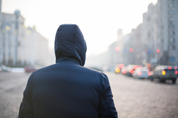 Lonely hipster man in hood walking on city street