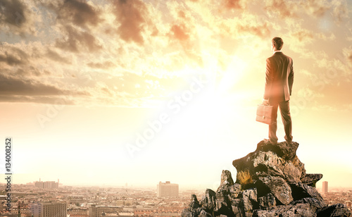 Fotografía Businessman standing with back against city