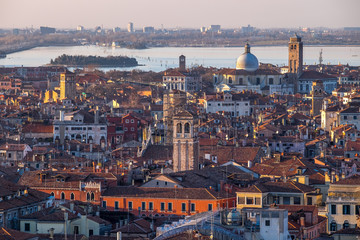 Wall Mural - Aerial view of Venice, Italy, at sunset with rooftops of building, the sea and warm sunlight.