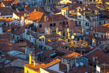 Wall Mural - Aerial view of Venice, Italy, at sunset with rooftops of building, the sea and warm sunlight.