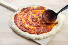 Pizza Baking , Spreading Tomato Sauce To Pizza Dough On Wooden Peel
