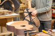 © asayenka - Serious professional guitar-maker working with unfinished guitar at workshop