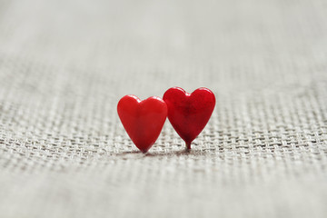 two red little hearts on the background of linen fabric