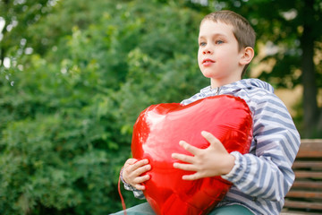 boy hugging a big red heart balloon. Valentine's day. empty space for your text