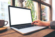© Farknot Architect - Mockup image of hand using laptop with blank white screen on vintage wooden table in cafe