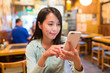 © leungchopan - Woman looking at mobile phone in Japanese restaurant