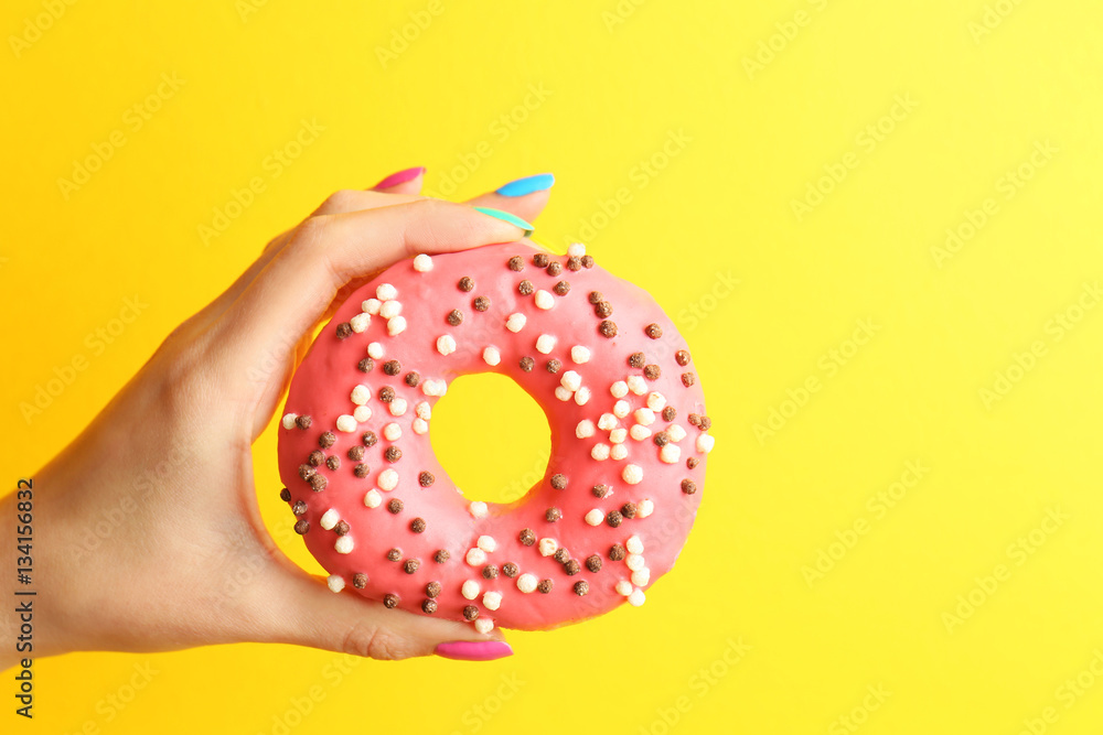 Woman holding delicious donut on color  background