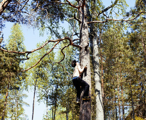 young brunette man climbing on tree with rope, lifestyle people 