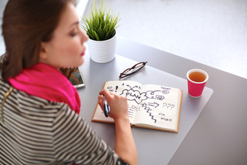 Young woman writes to diary on a white table