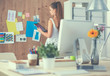 © shefkate - Young woman working in office, standing at desk