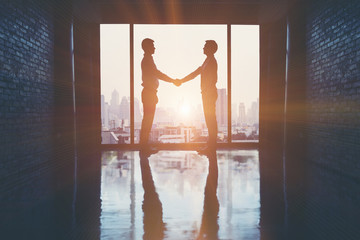 Businessmen handshake after the trade agreement in office on the building.
(silhouette)