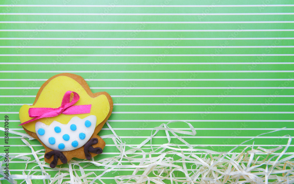 Decorative gingerbread Easter cookie with paper streamers on green striped background