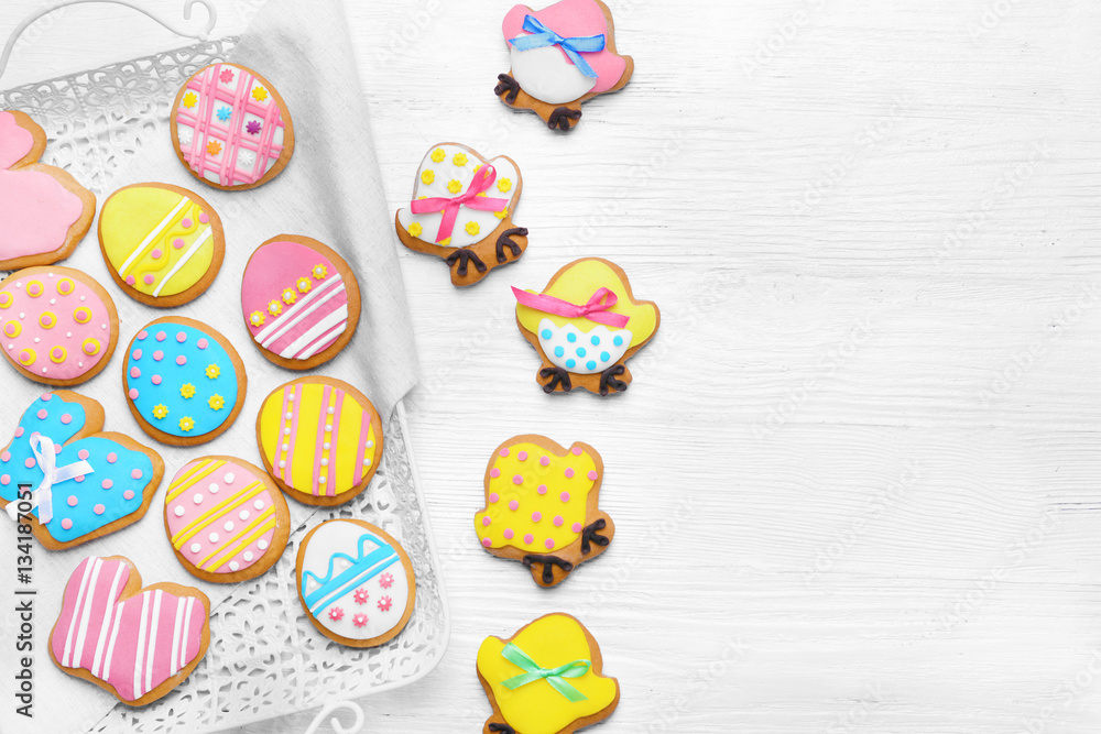 Delicious colourful Easter cookies on tray and white wooden background
