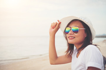 Young beautiful woman sitting on the beach wearing sunglasses. F