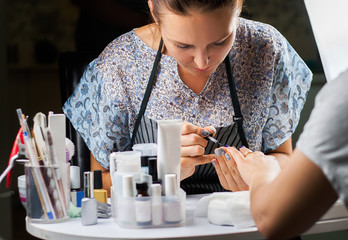 Woman in a nail salon receiving a manicure by a beautician