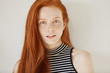 © WHstudio Leushin N - Youth and lifestyle concept. Close up portrait of attractive Caucasian teenage girl with long ginger hair and clean freckled skin wearing striped top posing against white studio wall. Horizontal