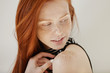 © WHstudio Leushin N - Highly-detailed shot of tender and cute teenage female with shy faint smile, loose ginger hair and and clean heathy skin looking over her shoulder while posing indoors against white studio wall