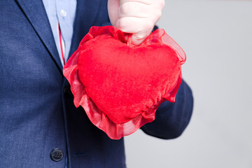 Young elegant man holding red heart on Valentine's Day.