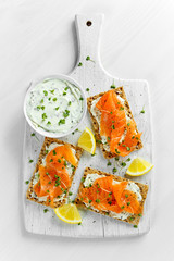 Wall Mural - Homemade Crispbread toast with Smoked Salmon, Melted Cheese and cress salad. on white wooden board background.