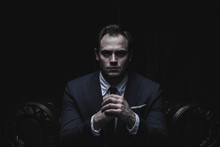 Portrait Of A Businessman Sitting On  Armchair  Black Background