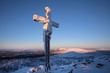 Cross on top of the mountain big Lusen covered in frost. View of the snowy mountain peaks, view from Lusen in Bavaria in the morning sun.