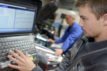 auto mechanic teacher and trainee performing tests at mechanic school