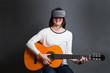 © Manuel - young woman learning how to play the guitar through virtual real