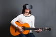 © Manuel - young woman learning how to play the guitar through virtual real