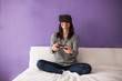 © Manuel - Young woman sitting on the bed at home having fun playing a virt