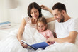 © Syda Productions - happy family reading book in bed at home