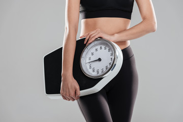 Closeup of sportswoman standing and holding weighing scale