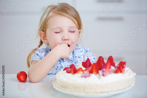 Plakat Dziecko smakuje truskawkowego tort w kuchni