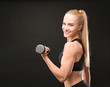 © Africa Studio - Young athletic woman with dumbbell on black background