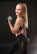 © Africa Studio - Young athletic woman with dumbbells on black background