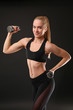 © Africa Studio - Young athletic woman with dumbbells on black background