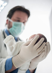 Wall Mural - Pediatrician holding a newborn baby boy in hospital