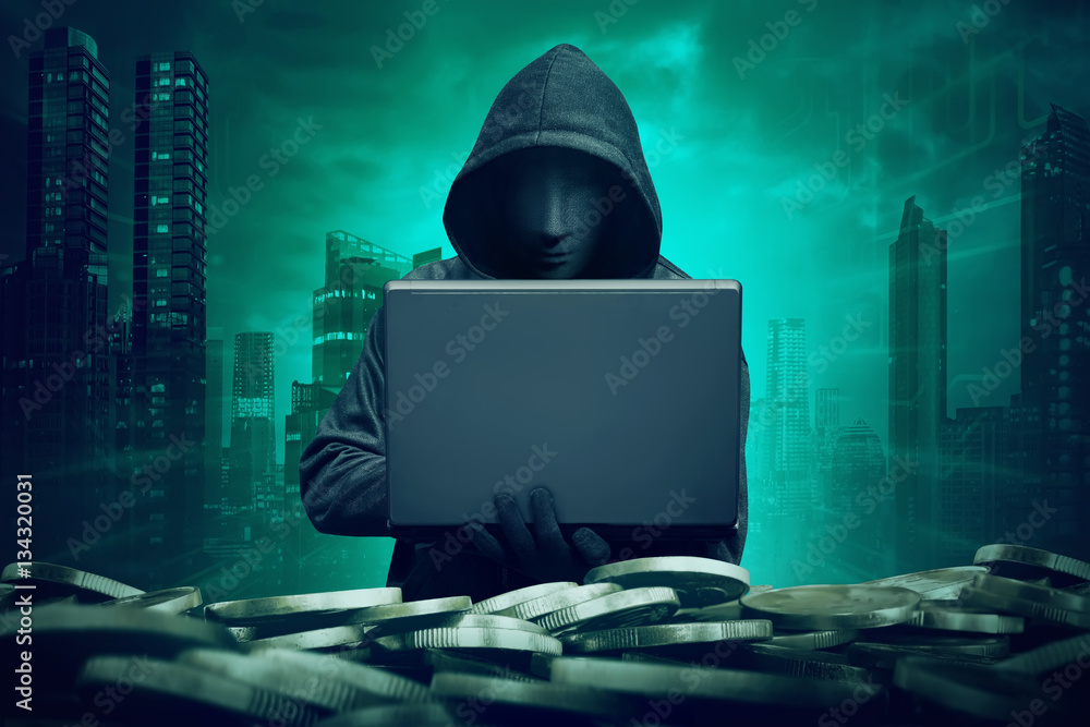 Hooded hacker with mask using laptop to hacking bank