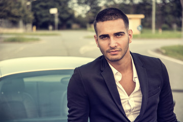 Wall Mural - Portrait of young attractiave man in business suit sitting in his new stylish car outdoor in countryside