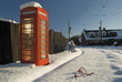 Old Style Red Telephone Box at side of snow covered road in living museum. 