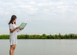 beautiful woman standing to read a map near lake