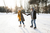 Senior couple in sunny winter nature ice skating.