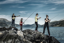 Young People Are Fishing On The Rocks Next To The Fjord, Norway