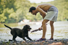 Man Playing Fetch With His Pet Dog Outdoors