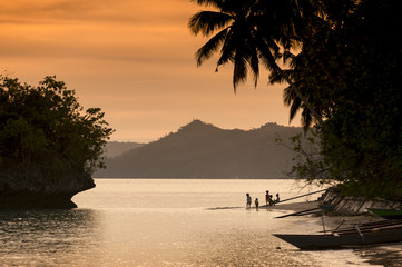 Wall Mural - Waigeo Island, Raja Ampat, Indonesia. This remote tropical island village called Saporkren is rarely visited by tourists. Sunset is the time for villagers to have fun in the water and enjoy nature.