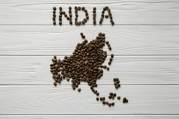  Map of the Indlia made of roasted coffee beans laying on white wooden textured background