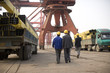 © Erickson Stock - Group of business people wearing hard hats walking along a wharf.
