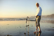 © Erickson Stock - Senior man standing on beach with walker